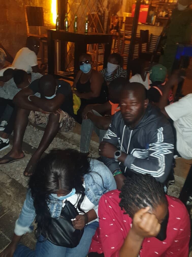 Ugandans under arrest sitting on the floor