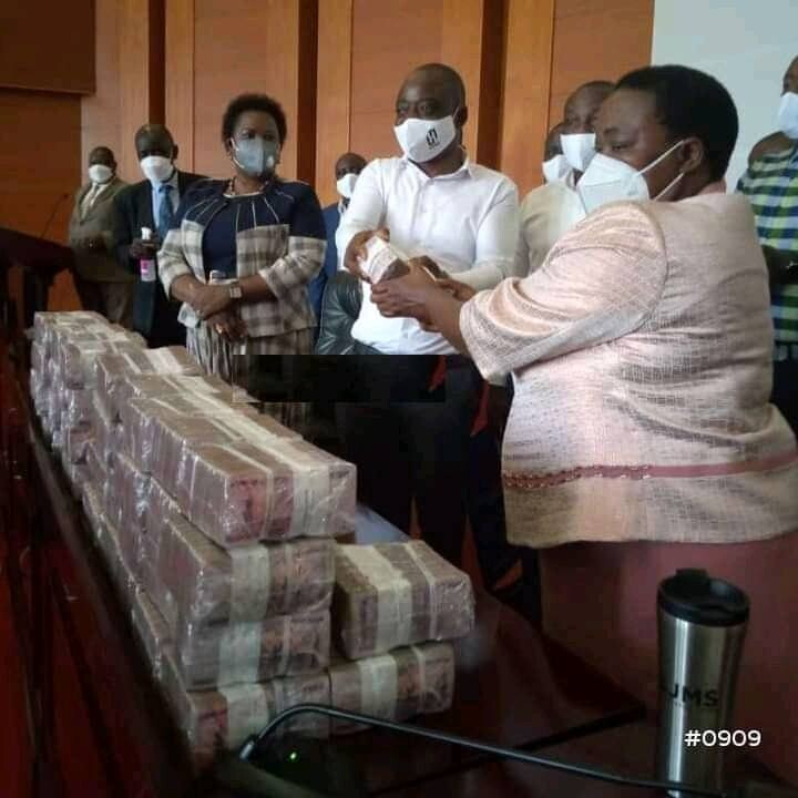 Hamis (white shirt) hands over money in bundles of 10 million to Nabbanja 